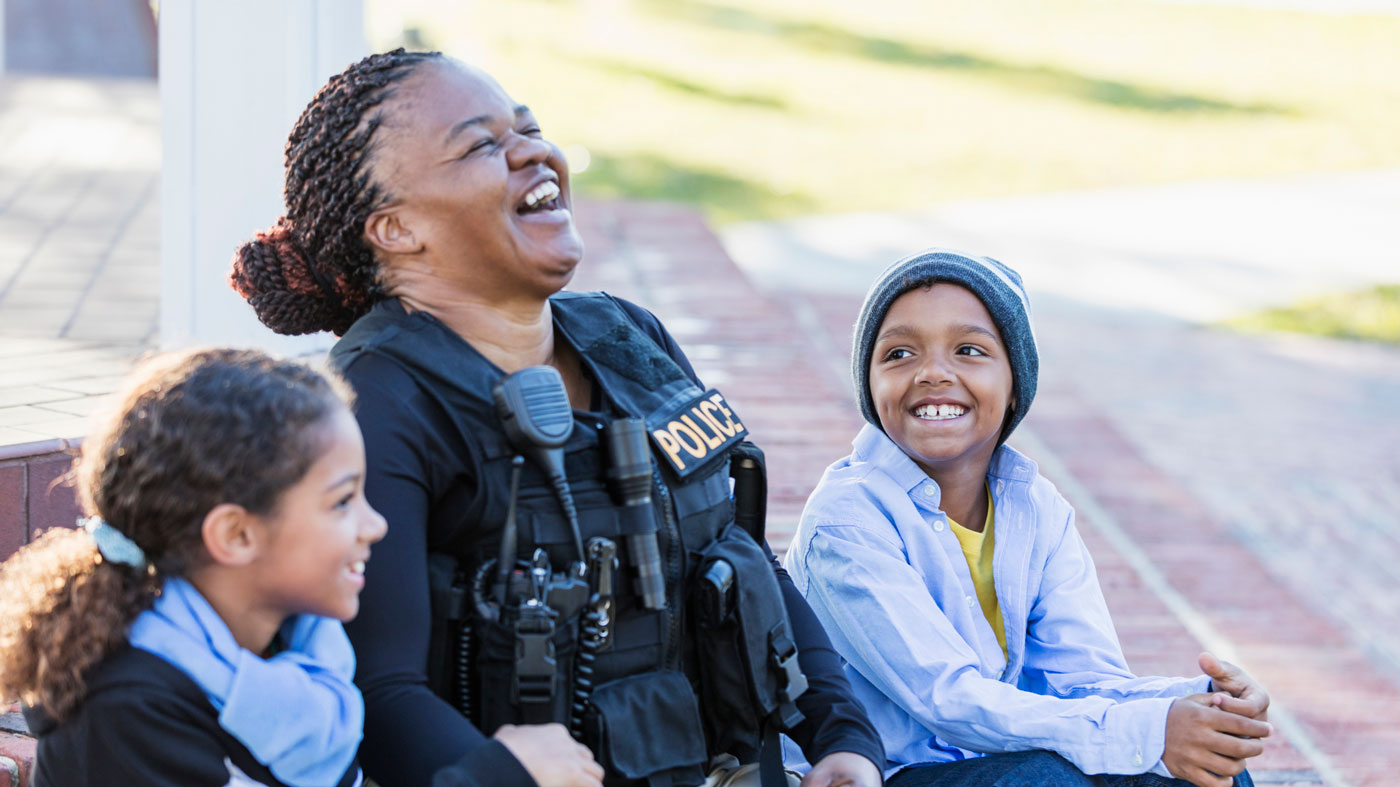 Police officer sitting and laughing with children 
